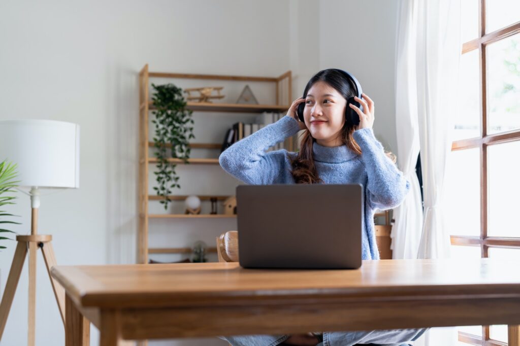 young attractive woman connecting the internet with a laptop at home she is wearing headphones and