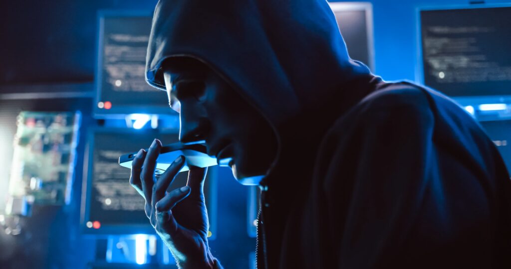 a hacker wearing a mask to cover his face is using computer to hack data to get ransom from victims