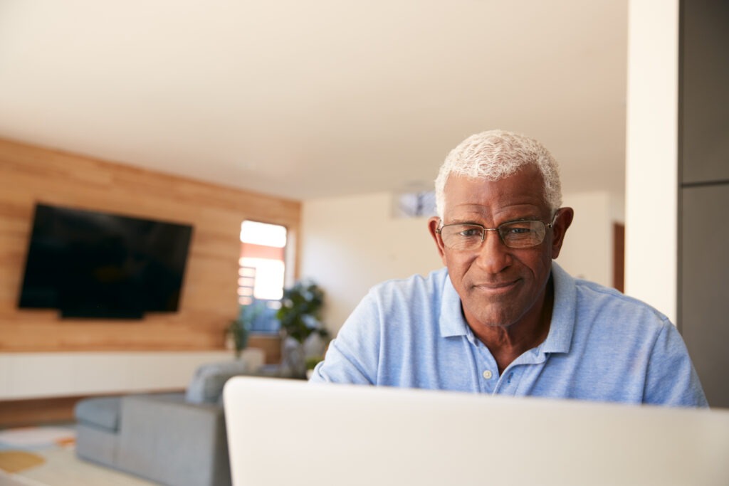 senior african american man using laptop to check finances at home
